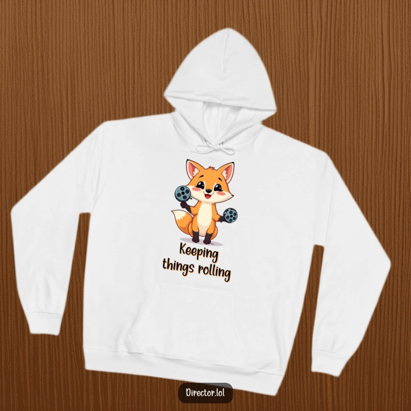 Funny hoodie showing a mischievous fox juggling film reels with a sly smile, perfect for adding warmth and humor to your day.